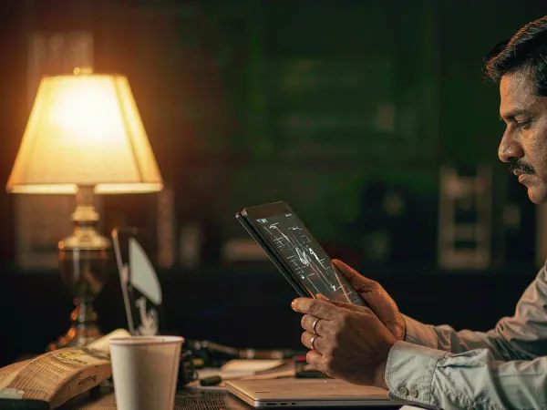lucky777 Man studies a tablet beside a cricket bat and coffee cup