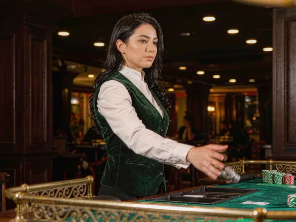 lucky777 Woman dealer reveals cards at a baccarat table with neat chip stacks